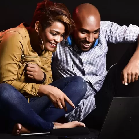 En man och en kvinna som sitter och tittar på en datorskärm och skrattar